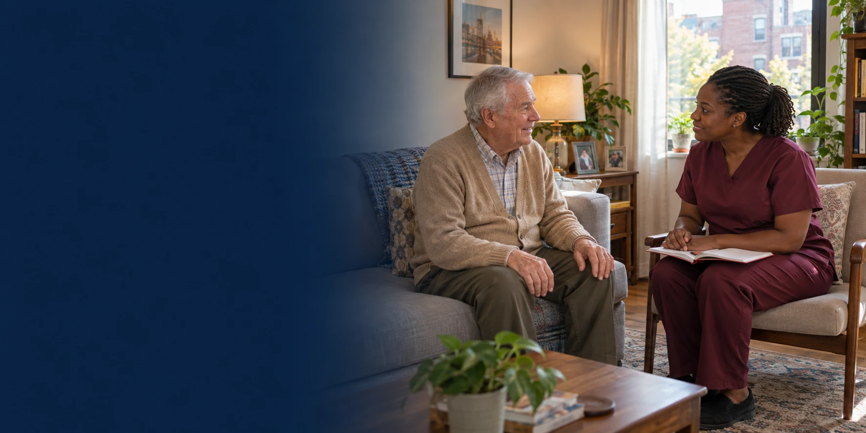 An older adult and a clinician with an open notebook talking together in a living room.