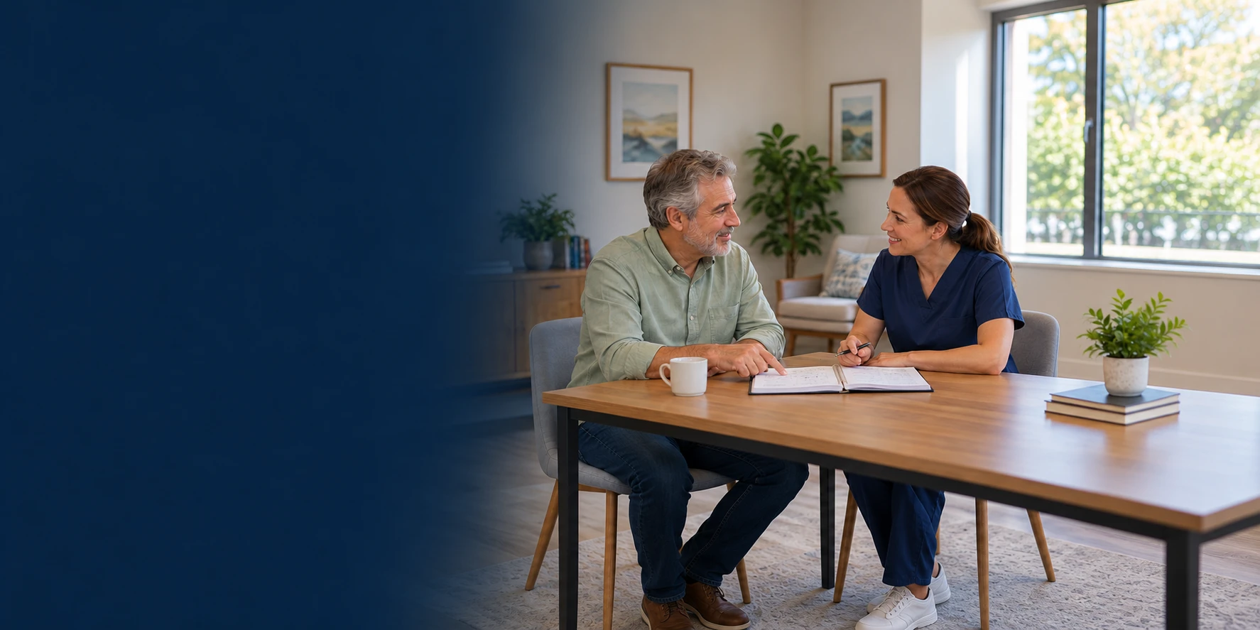 An adult patient and a clinician discuss an open notebook together at a consultation table.